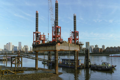 Cranes by river against sky