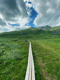 Scenic view of landscape with wooden walkway against sky