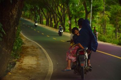 Rear view of girl with mother and father on motorcycle