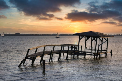 Pier over sea against sky during sunset