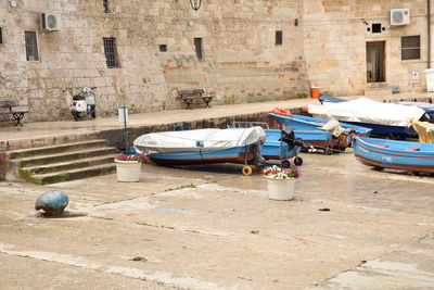 Boats moored on street by buildings in city