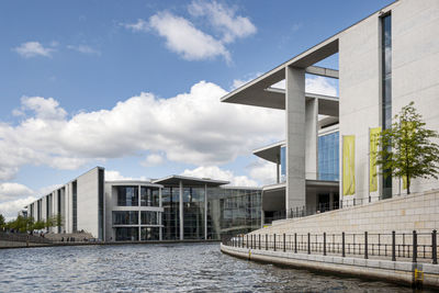 Bridge over river by buildings against sky