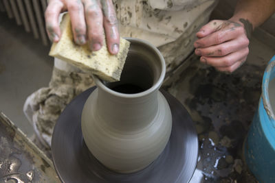 Midsection of man making earthenware in workshop