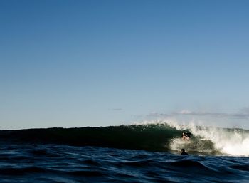 Man surfing in sea against clear blue sky