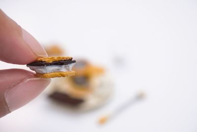 Close-up of hand holding ice cream over white background