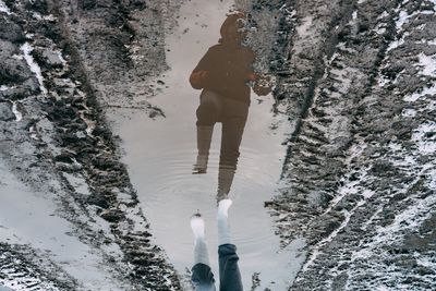 Low section of man walking over puddle