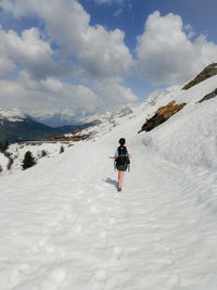 Rear view of person on snowcapped mountain against sky