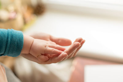 Close-up of baby holding person hands