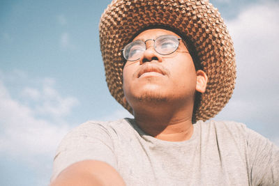 Portrait of young man wearing hat against sky