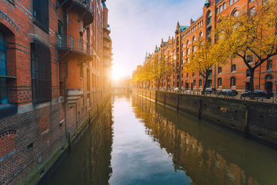 Canal amidst buildings against sky during sunset