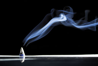 Close-up of burning candle against black background