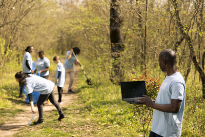 Rear view of man using digital tablet while standing in park