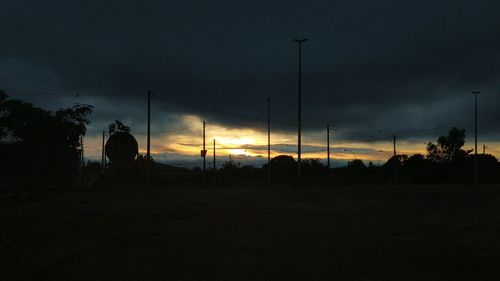 Silhouette trees on field against sky at sunset