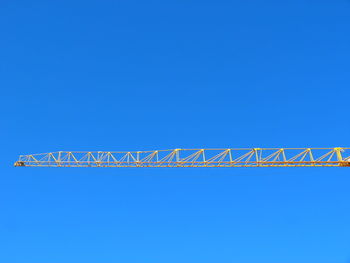 Low angle view of crane against clear blue sky