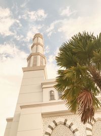 Low angle view of palm tree and building against sky