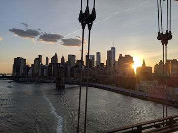 View of river and buildings against sky during sunset