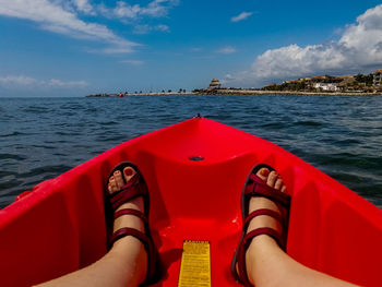 Low section of woman in boat on sea against sky