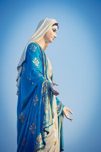 Low angle view of woman standing against blue sky