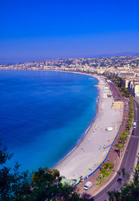 High angle view of sea and city against blue sky