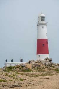 Lighthouse by sea against clear sky