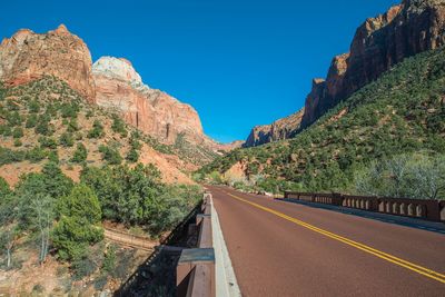 Road amidst rocks and mountains against clear blue sky