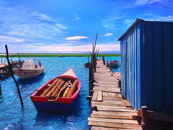 Logs in boat moored on river against sky