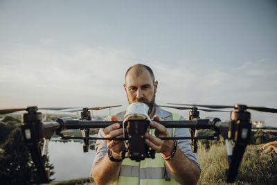 Man holding drone while standing against sky