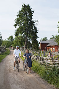 People on road amidst trees against sky