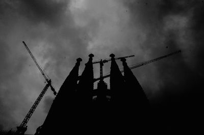 Low angle view of silhouette cranes against sky