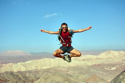 Full length of man jumping over landscape against sky
