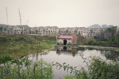 Buildings by lake against clear sky