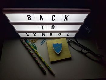 High angle view of illuminated sign with school supplies on table