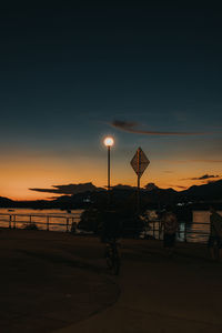 Silhouette street lights against sky at night during sunset