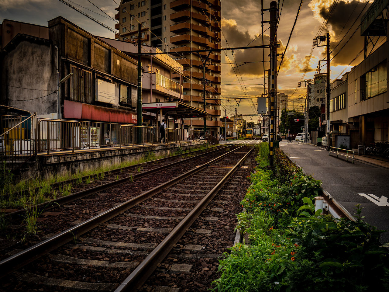 building exterior, architecture, built structure, railroad track, track, rail transportation, transportation, building, sky, city, nature, mode of transportation, residential district, no people, cloud - sky, outdoors, direction, plant, electricity, sunset, long