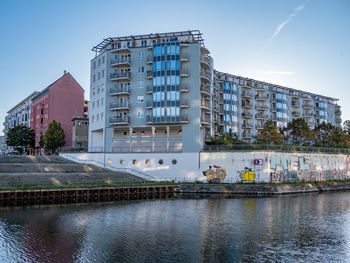 Buildings by river against sky