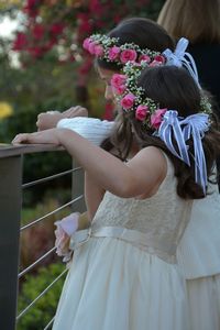 Girls wearing flowers standing by railing