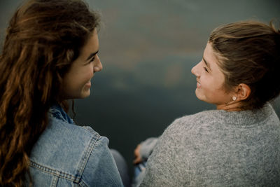 High angle view of smiling siblings talking against lake