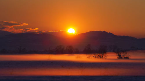 Scenic view of lake against orange sky