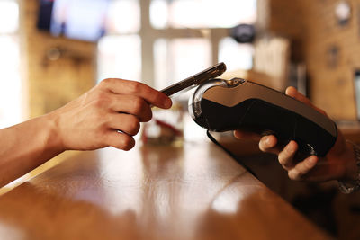 Cropped hand of woman using mobile phone on table