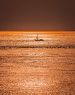 A fishing boat sails across the north sea at sunset