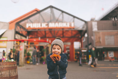 Smiling boy holding food while standing outdoors 