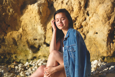 Portrait of a young woman sitting on rock