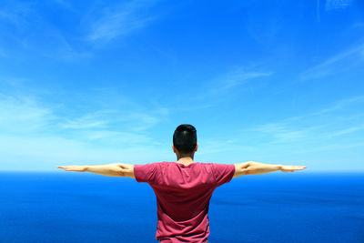Rear view of man standing against blue sky