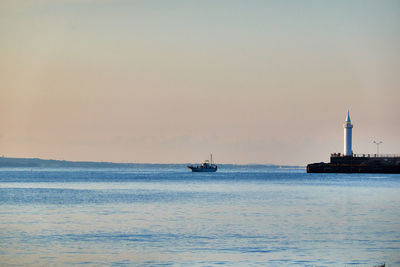 Scenic view of sea and ship against sky during sunrise