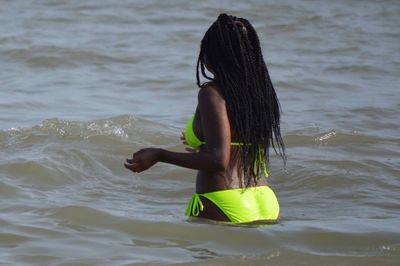 Rear view of woman in bikini with long braided hair standing in sea