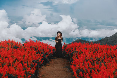 Rear view of woman walking on field against sky