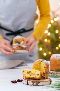 Traditional italian christmas cake panettone on a rustic table. female hands are holding cake