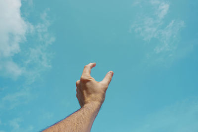 Low angle view of hand against sky