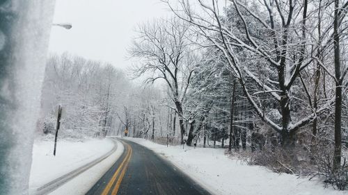 Road amidst snow covered trees during winter