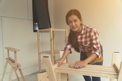 Portrait of smiling young woman standing against wall at home